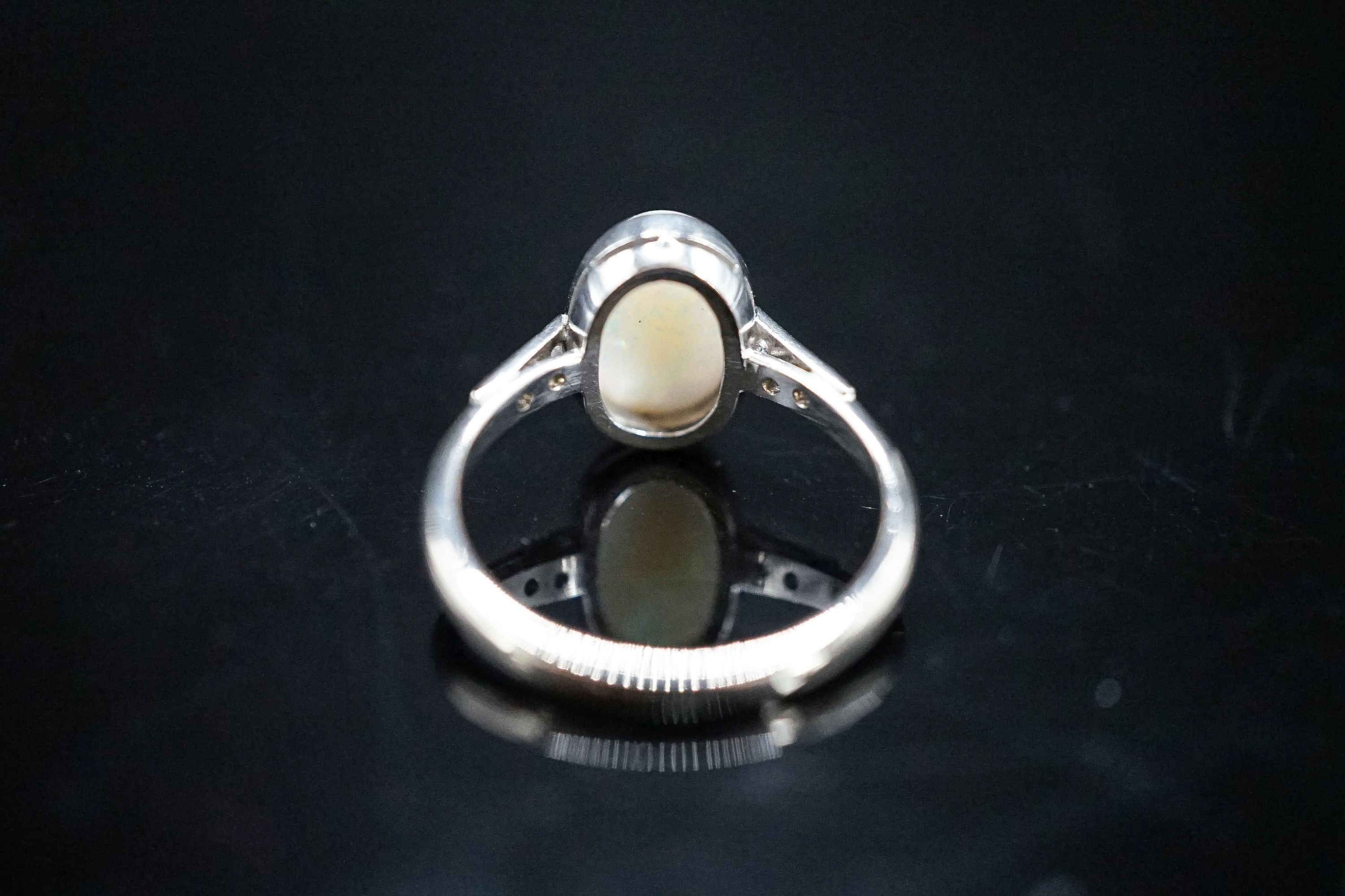 A white metal and white opal set oval ring, with diamond set shoulders, size M, gross weight 3.4 grams.